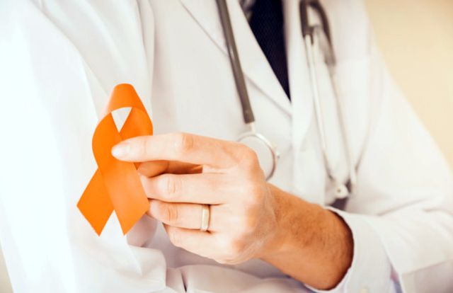 Доктор держит в руках оранжевую ленточку как символ рассеянного склероза