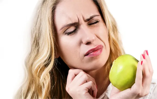 Женщина с яблоком мучается от боли в дёснах