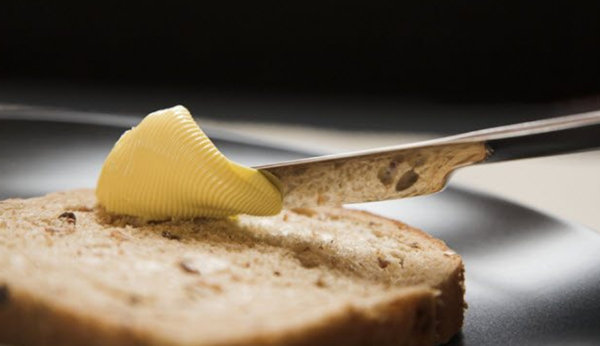 Намазывание маргарина на кусок хлеба