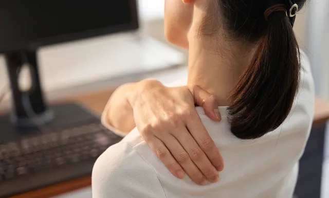 Женщина-бизнесмен у которой болят плечи от работы на дому за компьютером