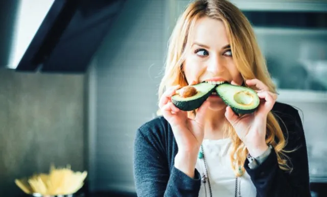 Женщина старше 40 лет объедается авокадо